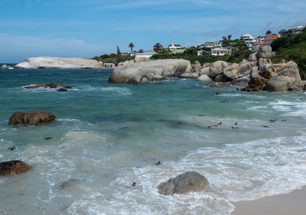 Durban beachfront accommodation near the beach, with turquoise waves rolling onto white sand and houses on the hillside above